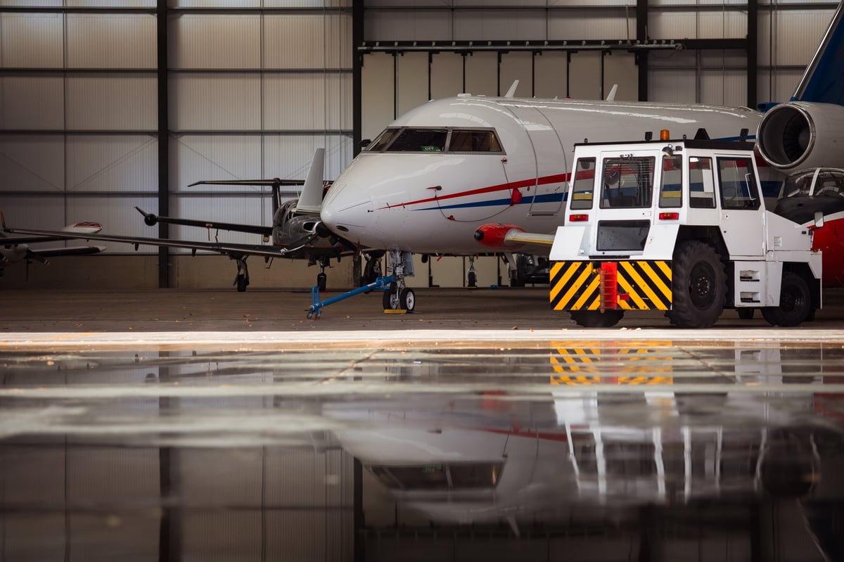 Corporate flight department team reviewing operations in a modern hangar with a business jet in the background